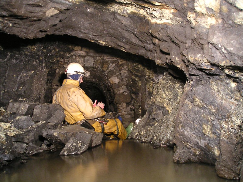 bs_testingair_deeplevel_blockage.jpg - Karli getting his matches out to see if they light, they did not! The smoke from them made the air even worse. This is only 3m or so from the the end. There is a very good flow of water here and we removed some of the rocks to lower the level.