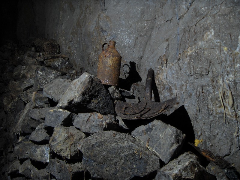 cc14_stope_shoesspade.jpg - A can shovel and iron clog shoes, with a draping of dry rot.