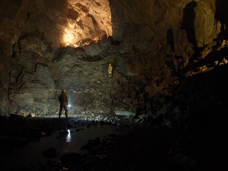 P8241462.JPG - East end of the main chamber. Myself and Pete climbing up. Photo by Karli.