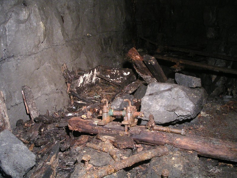 rg_ramseyssp_engineroom2.jpg - In the engine room we can see some fittings still attached to their wooden bed. In the background there is a wooden box with fittings and parts of piping in it.