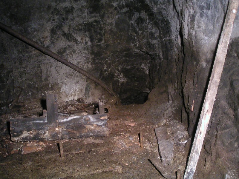 rg_rgshaft_engineroom2.jpg - The passage wit the pipe is where you enter the engine room above Rampgill Shaft. The remains of a wooden storage box can be seen towards the left.
