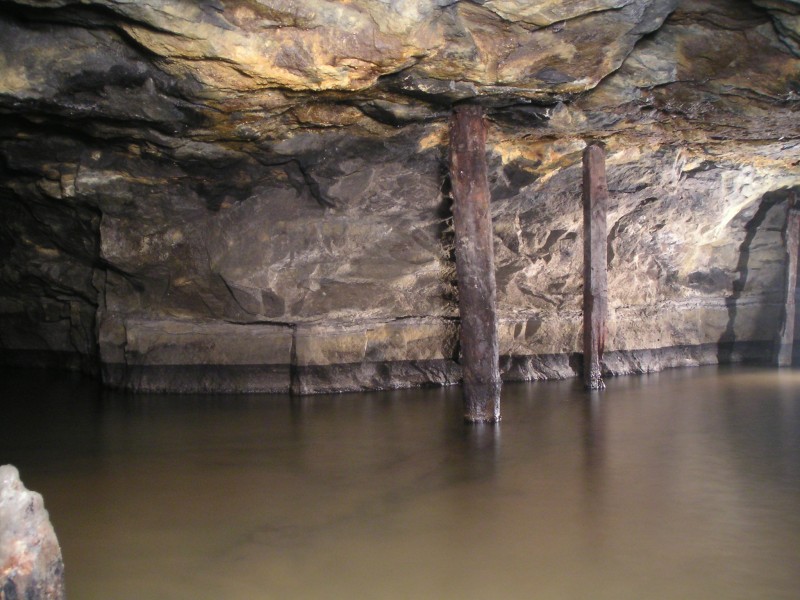 sc_1SV_junct_to_2SV.jpg - Just past Wharton's Sump you reach the junction for the 2nd Sun Vein heading towards the right. Straight on or left heads east to the forehead of the 1st Sun Vein. The wooden supports here are for the air pipe which is submerged, it can just about be seen as the dark area in the water.