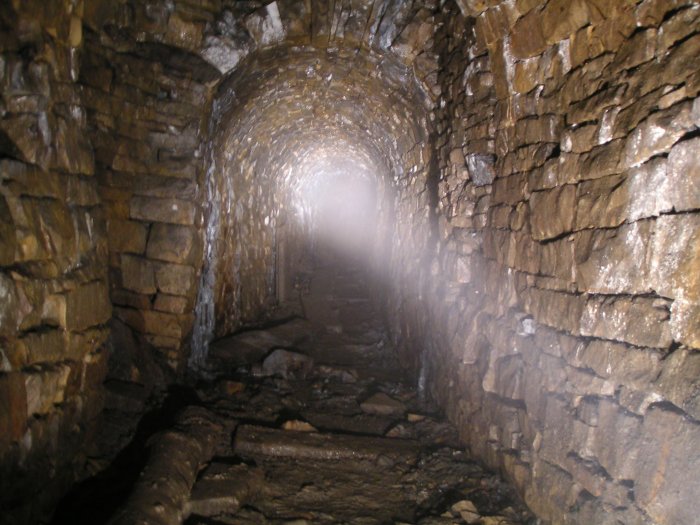 doublerise_sublevel2.jpg - Looking down the sublevel past the Double Rise. It is possible to make out some of the remains of old wooden barrow planking. Due to the still air our breath quickly started to cause a fog up.