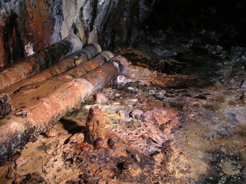 sc_middlecleugh_stopes_staligmites.jpg - To the right of the bucket was this pile of air pipes and some colourful calcification on the floor including some stalagmites, not often seen in Smallcleugh.