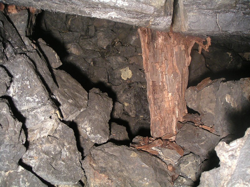 sc_wfs_2ndstopelevel2.jpg - A rotten roof support on the other side of the low end of the stope, the arch and slope are just before it on the left hand side - it does look like it goes on to the left past the support.