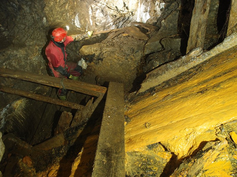 P4023406.JPG - Mucky ore chute at the top of a manway. Behind Karli is the way on into a large flat.