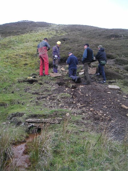 olrb_drain.jpg - The small drainage adit for the Old Level, with everyone gathered by the entrance.